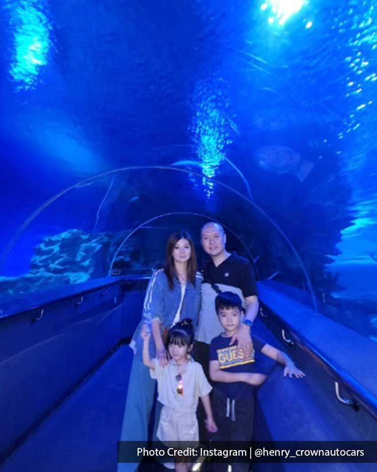 Family posing in Aquaria KLCC underwater tunnel, an entertainment attraction near Imperial Lexis Kuala Lumpur