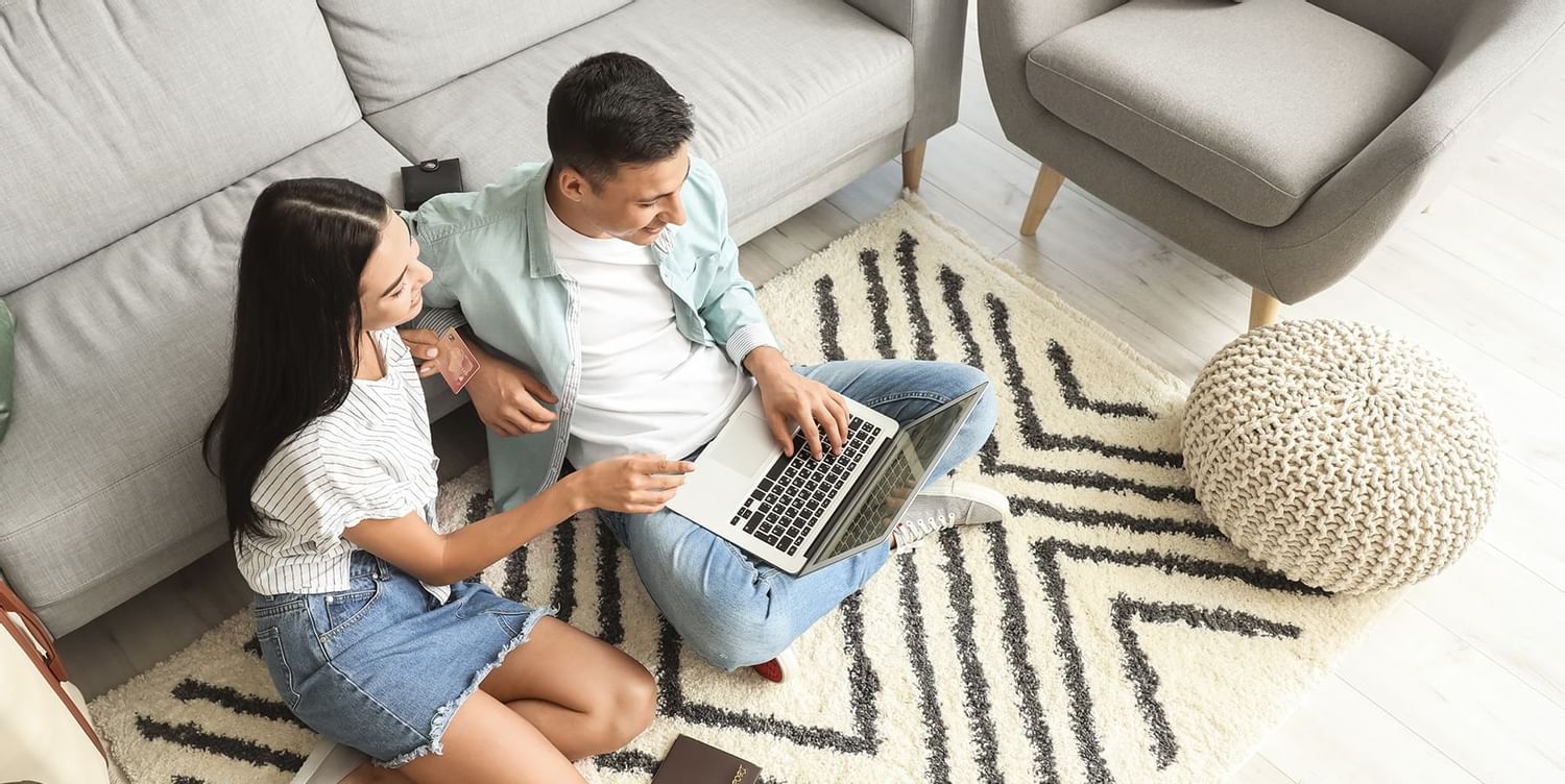 Couple looking into a laptop in a room at Coast Fort St.John