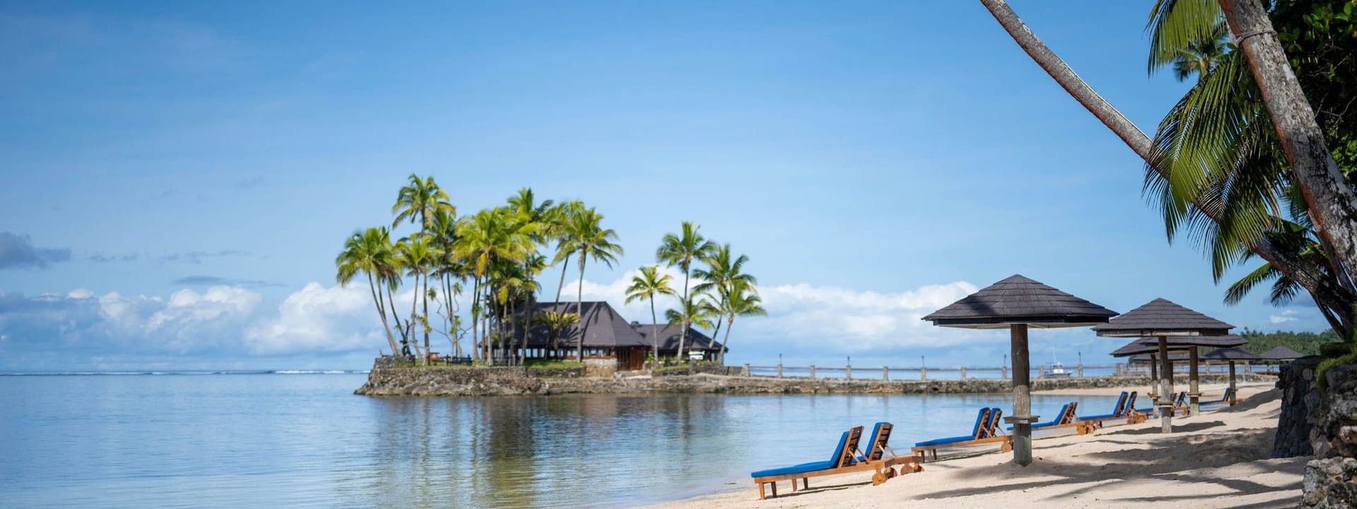 Sandy beach with lounge chairs and umbrellas at Warwick Fiji Resort and Spa in Korolevu