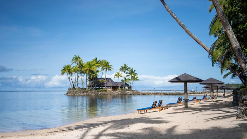 Sandy beach with lounge chairs and umbrellas at Warwick Fiji Resort and Spa in Korolevu.