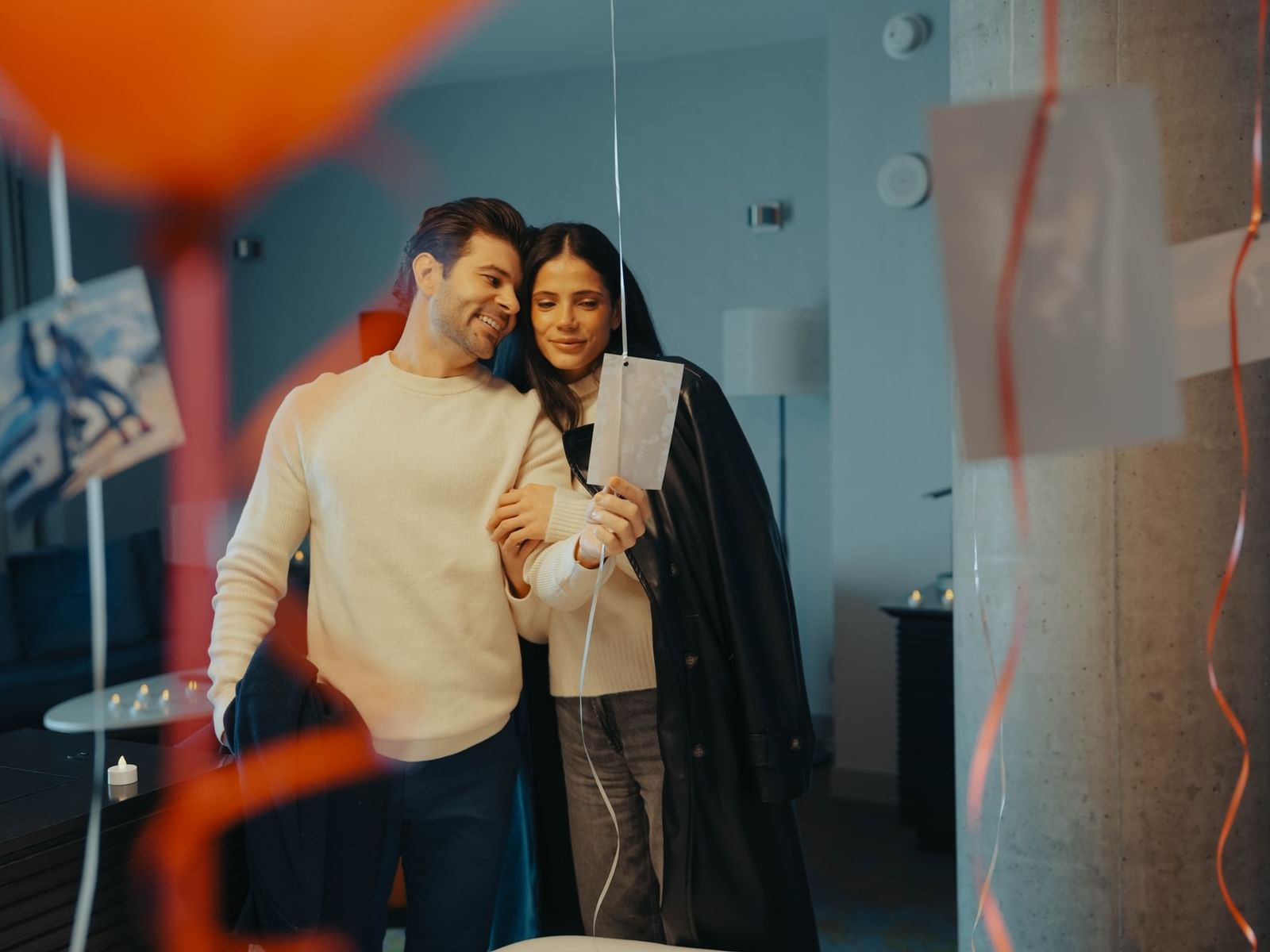 Couple standing in-room looking at photos included in the 