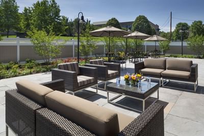 Outdoor patio with wicker furniture, umbrellas, and landscaped gardens at Aramark Chauncey Conference Center