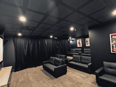 Modern cinema room with black leather seating, projection screen, and vintage movie posters at UniLodge Herston