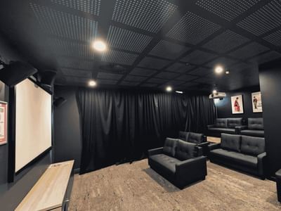 Black cinema room with leather couches, posters, and projection screen at UniLodge Herston
