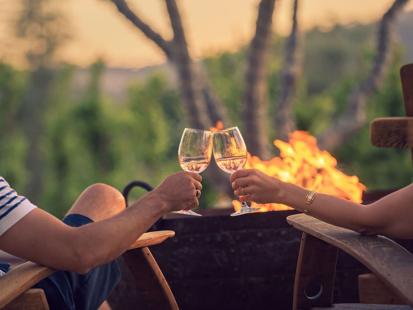 Two people enjoying wine in front of firepit