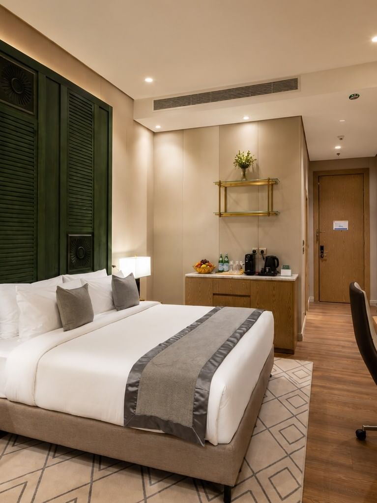 King bed facing wall TV beside desk in Deluxe Room at Naviti by Warwick Jeddah, featuring spacious hotel rooms in Jeddah