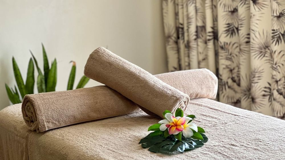 Towels and tropical flowers on spa bed at The Joy Spa, The Naviti Resort - Fiji, Korolevu.