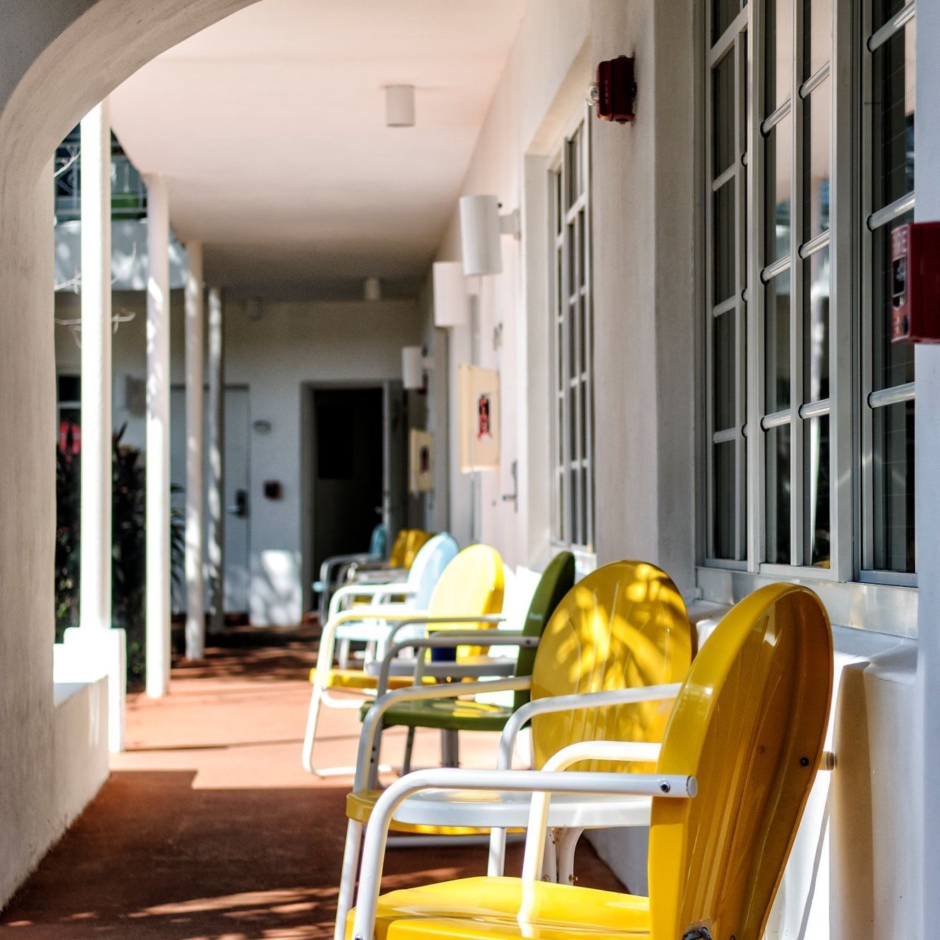 Outdoor walkway balcony with brightly colored yellow and green chairs offering a sunny spot at Tradewinds Apartment Hotel