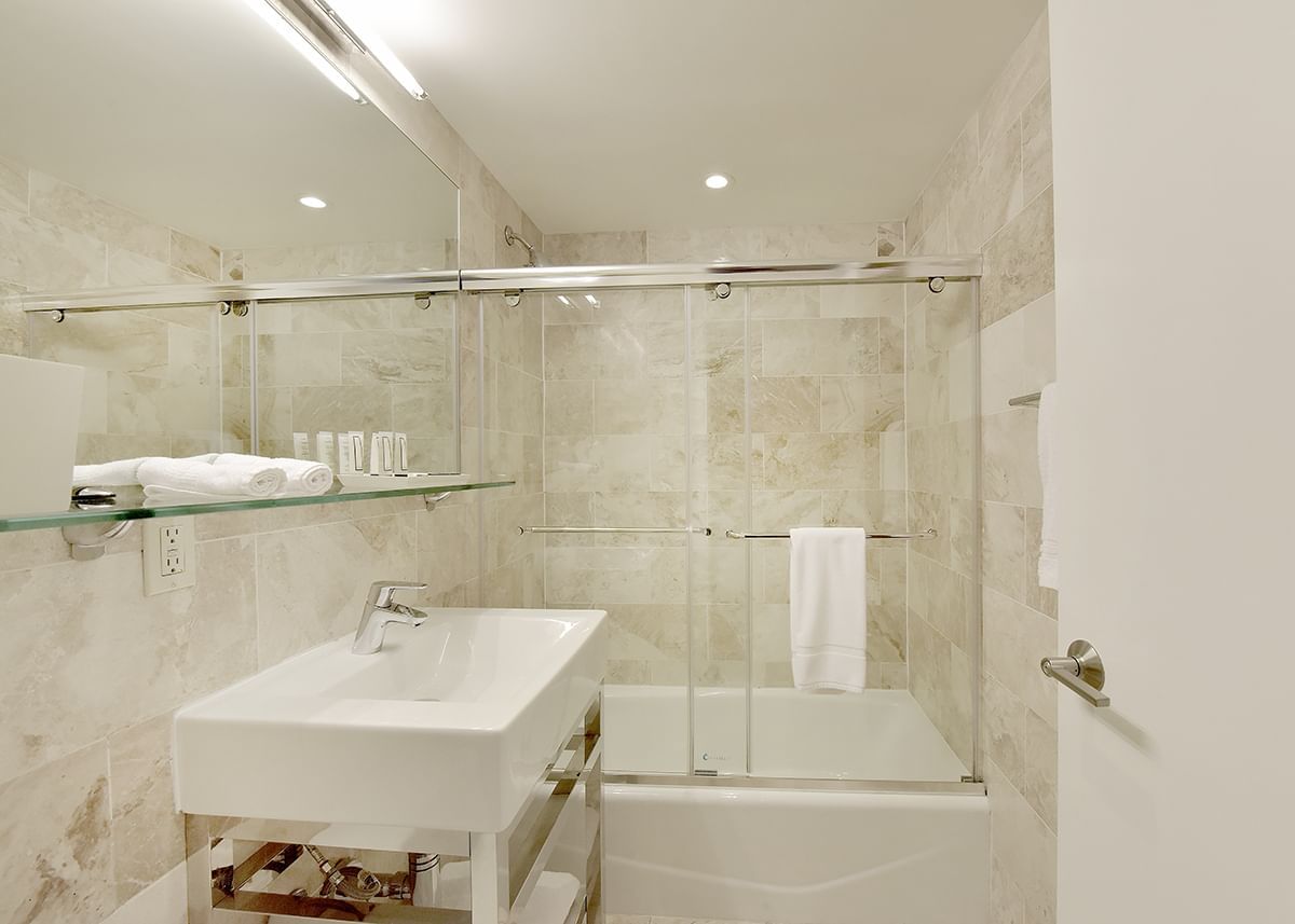 A clean bathroom with a white sink, a glass shower door, and a bathtub.