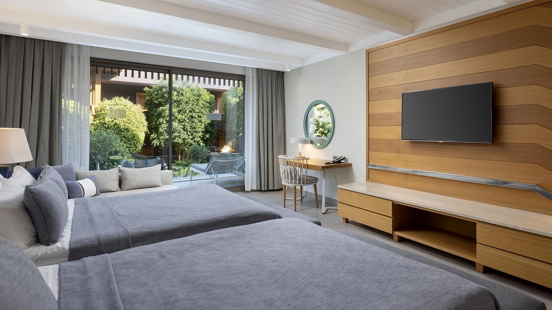 Swim-up Superior Room with two beds, a desk, and a TV in a hotel room with large windows and a balcony at Titanic Luxury Collection Bodrum..