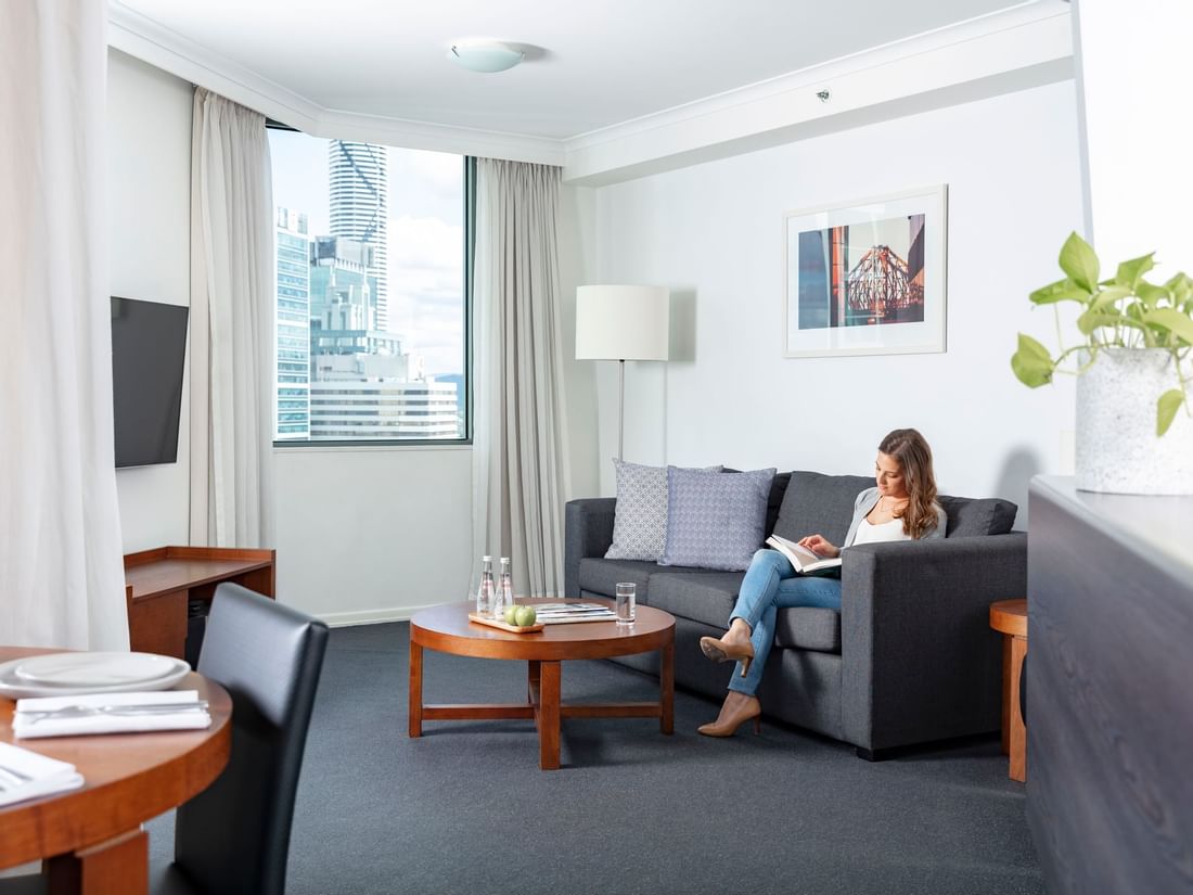 Lady reading book on the sofa at Sebel Suites Brisbane