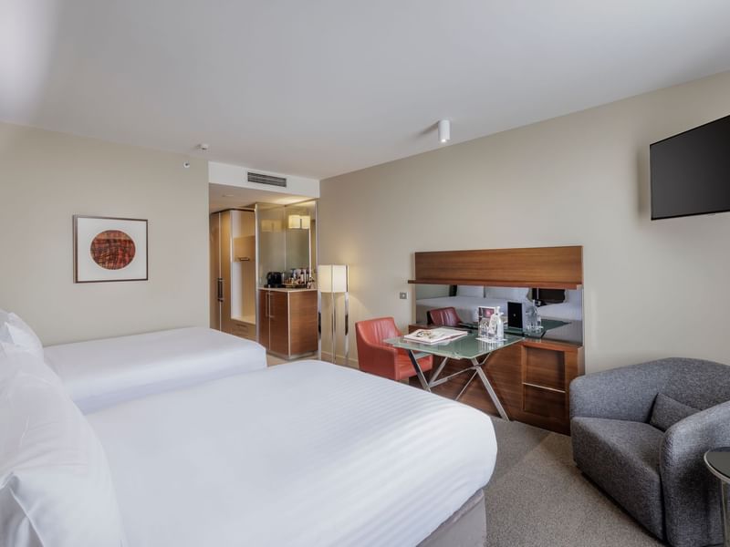 Wall-mounted TV with work desk facing two beds in Deluxe Room - Two Double bed at Pullman Sydney Olympic Park
