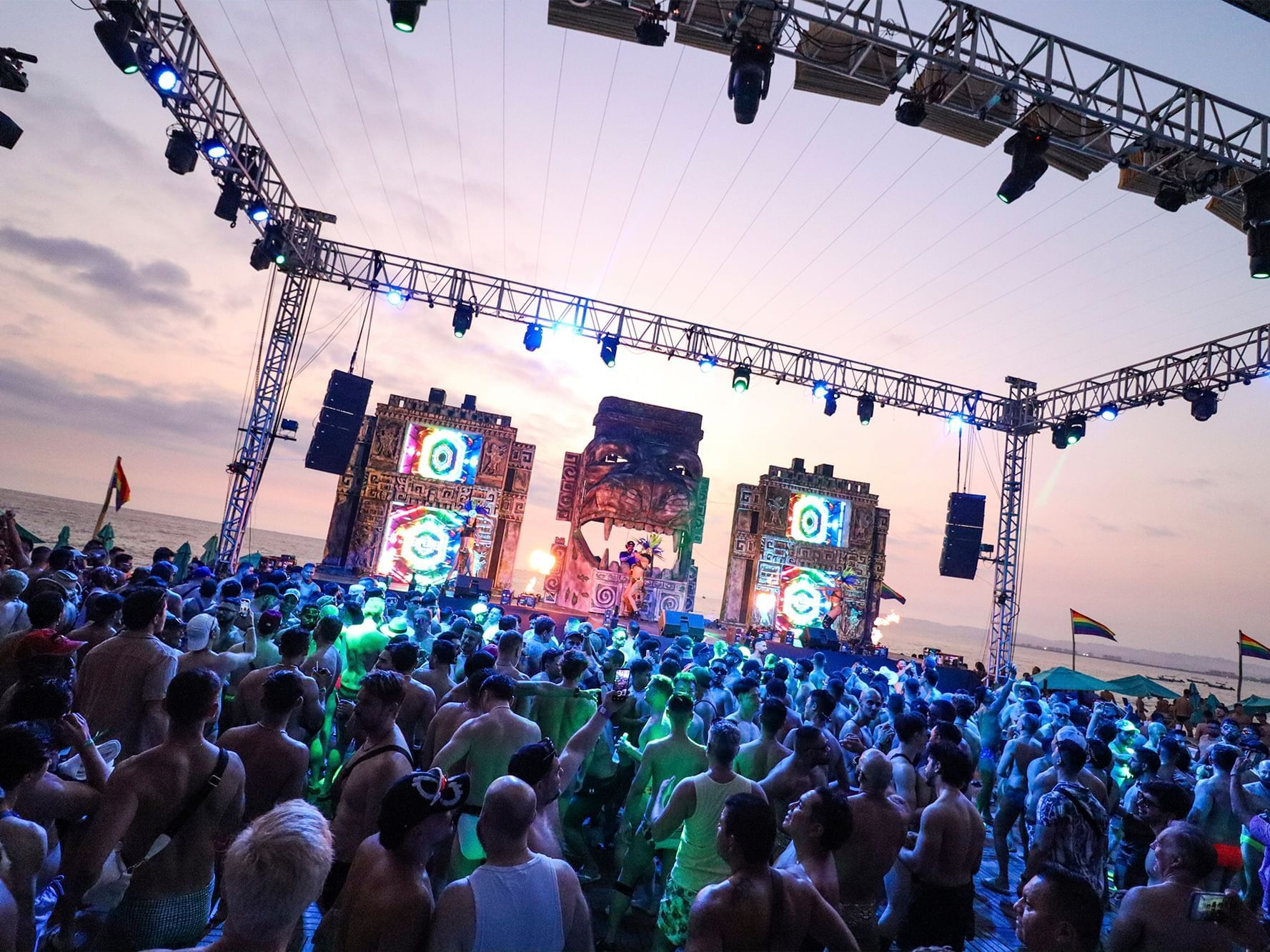 A crowded sunset beach party with a large stage and lights at the Almar Resort a popular gay resort in Puerto Vallarta Mexico