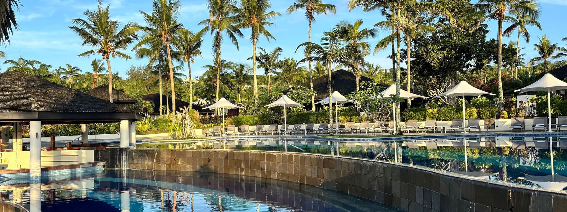 Tropical resort pool with palm trees and beach chairs at Warwick Le Lagon Efate