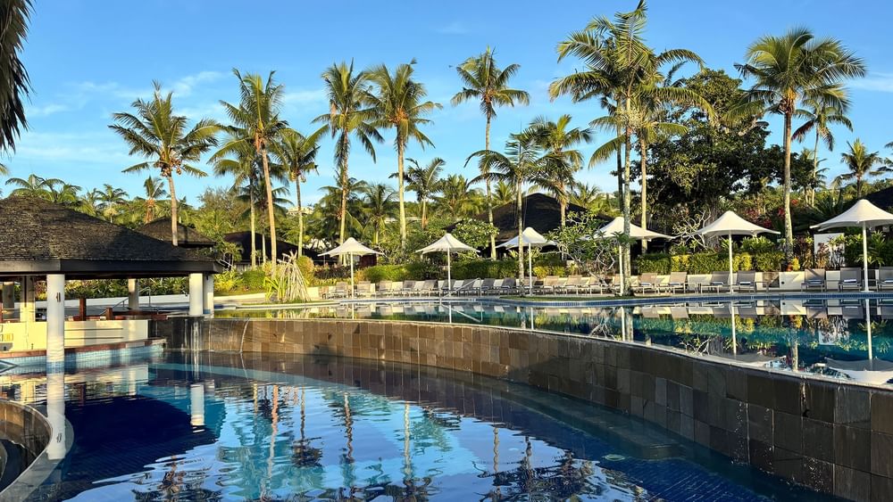 Tropical resort pool with palm trees and beach chairs at Warwick Le Lagon Efate.