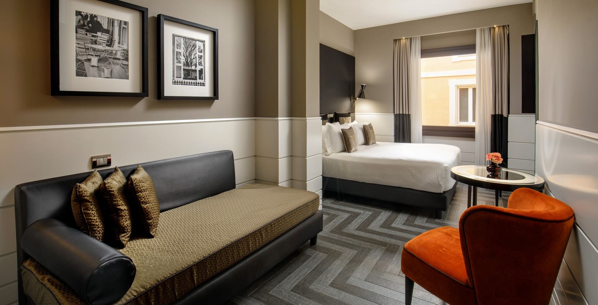 King Bed Premium room at Tribune Hotel Rome with elegant modern décor, comfortable king bed, lounge area with sofa and armchair, and warm natural light.