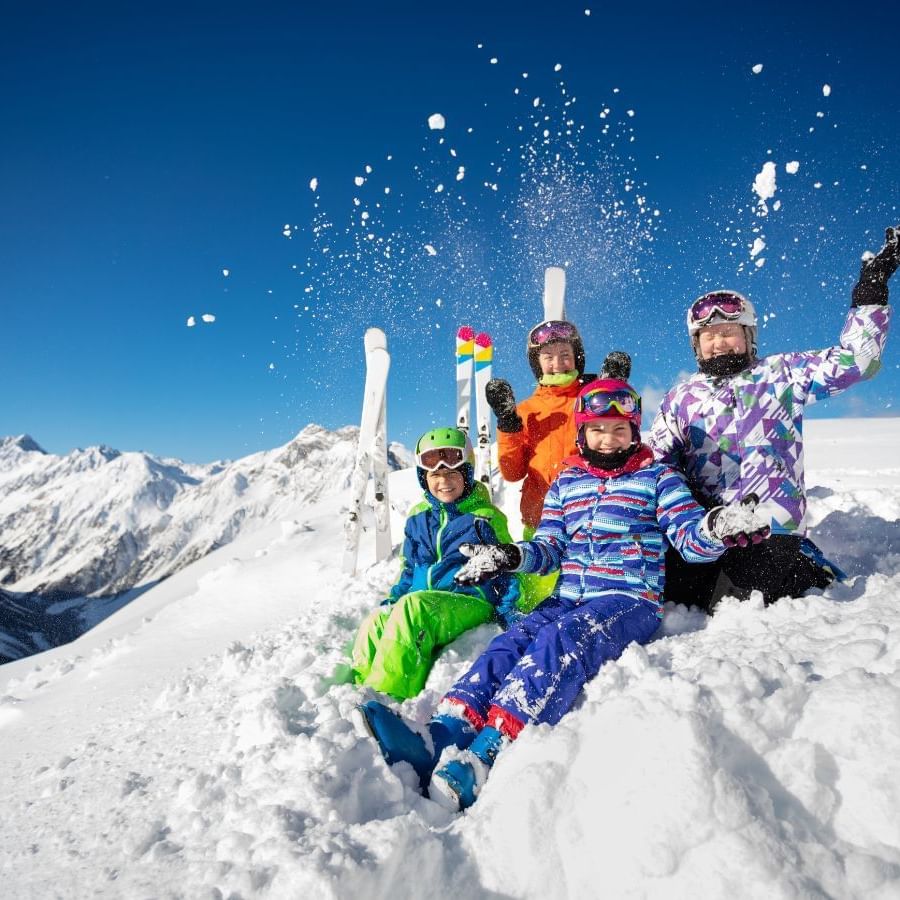 Family posing by a snow slope with skis near Blackcomb Springs Suites
