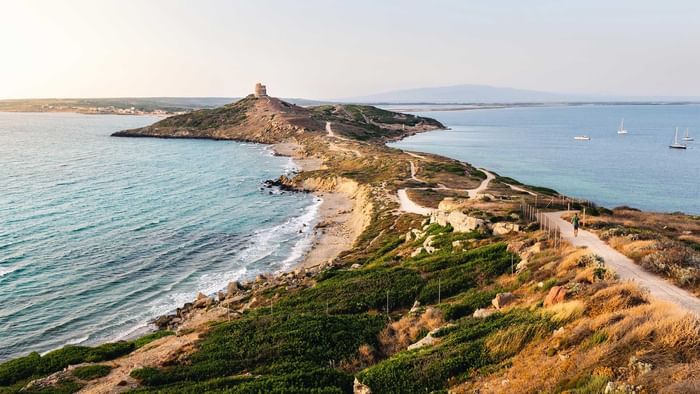 Coastal view of a peninsula with beach & sailboats in Sardinia near Falkensteiner Resort Capo Boi