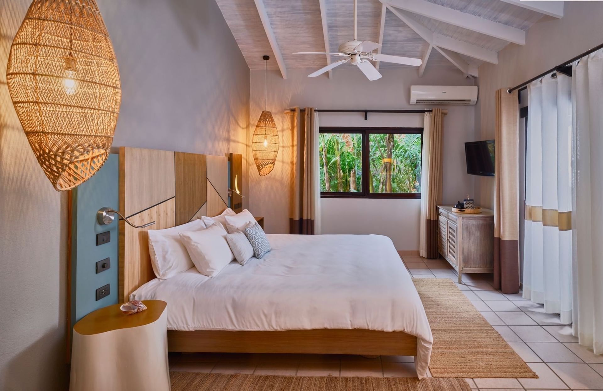 A comfortable room with a large bed and tropical view at Cala Luna Boutique Hotel.