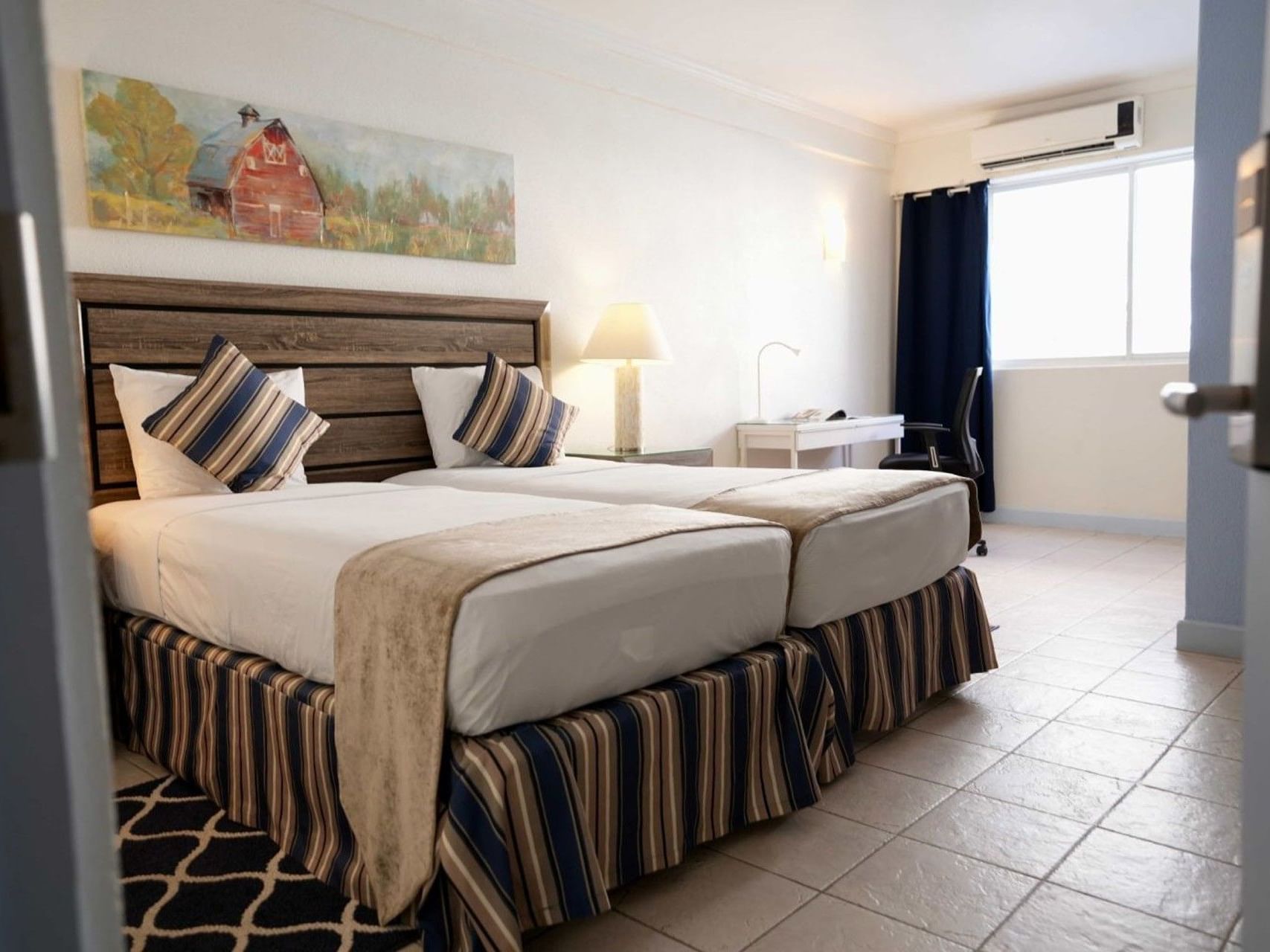 Bright Standard Room with striped bedding, wooden headboard, and tiled floors at Time out Hotel in Oistins.