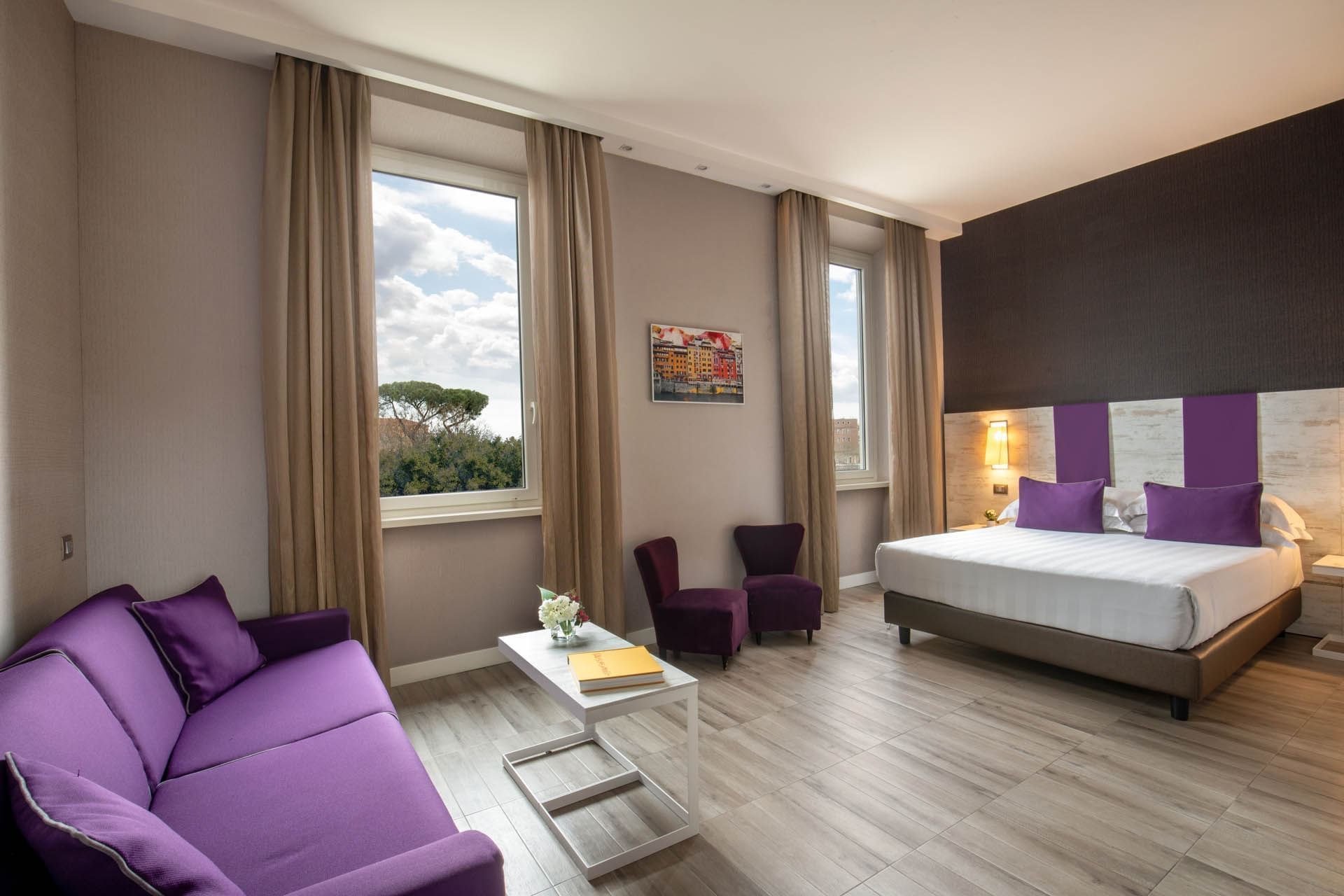 Modern Family Room at The Guardian Hotel with a comfy bed, a sofa, and large windows offering an outdoor view