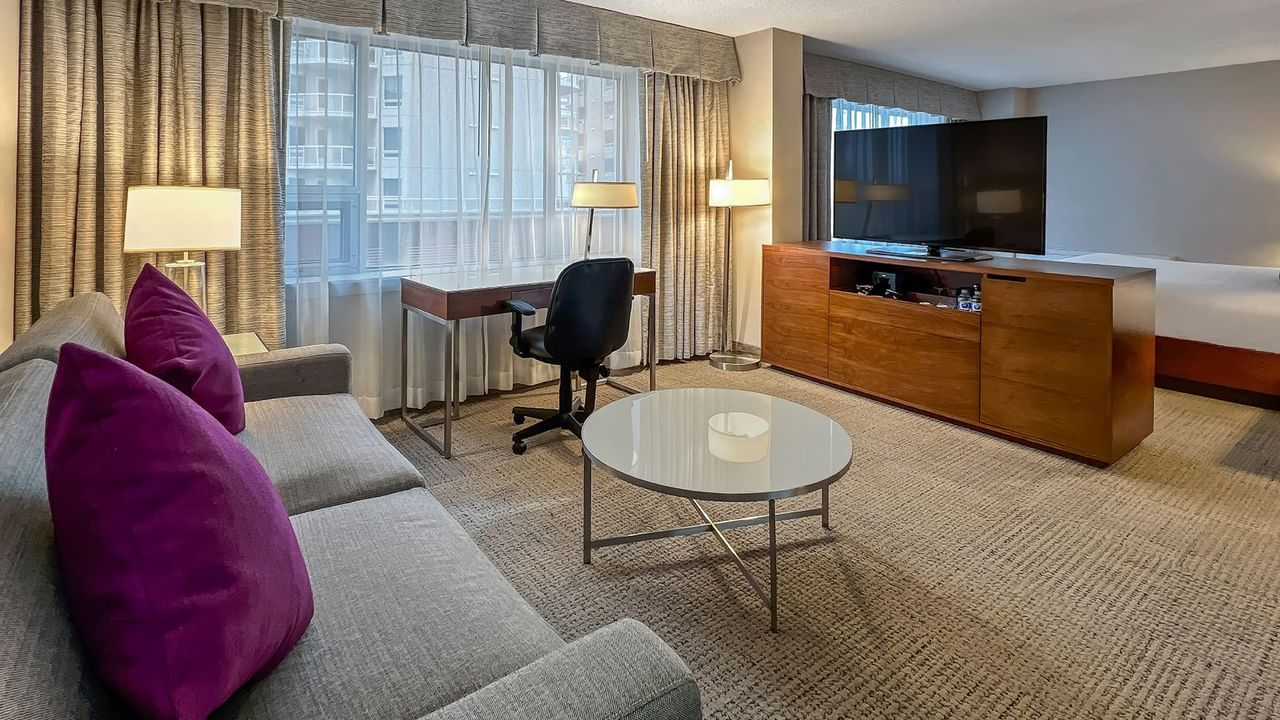 Sofa, desk, TV, bed, table in a hotel room