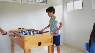 A boy playing soccer table in a game room at Fiesta Resort