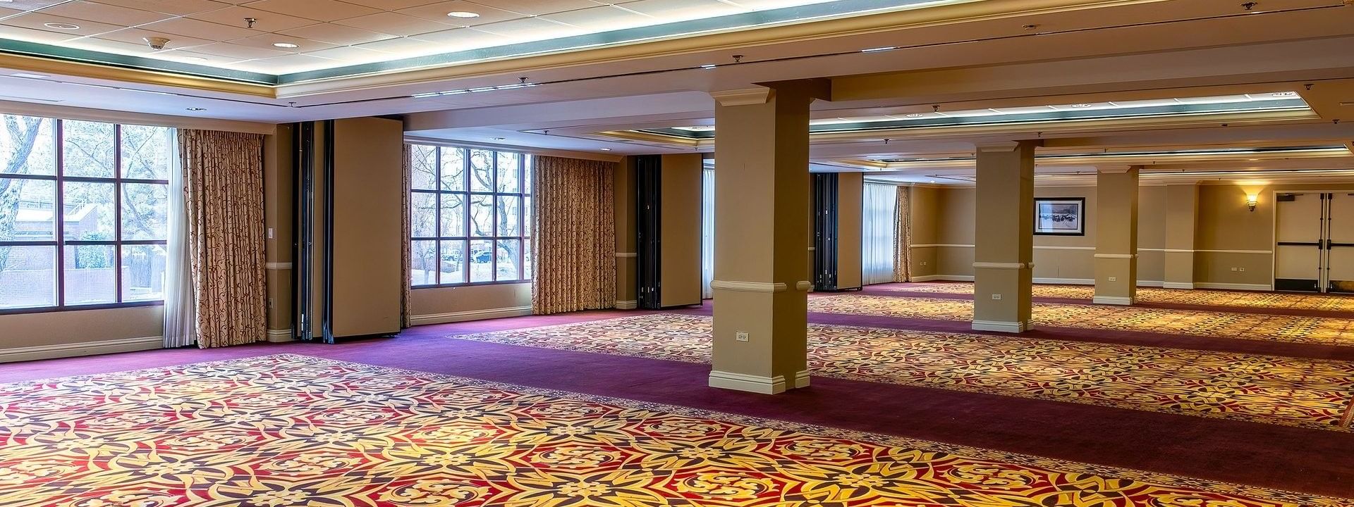 Large empty ballroom with patterned carpet and pillars under soft lights in Capitol II/III/IV at Warwick Denver
