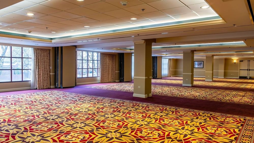 Large empty ballroom with patterned carpet and pillars under soft lights in Capitol II/III/IV at Warwick Denver