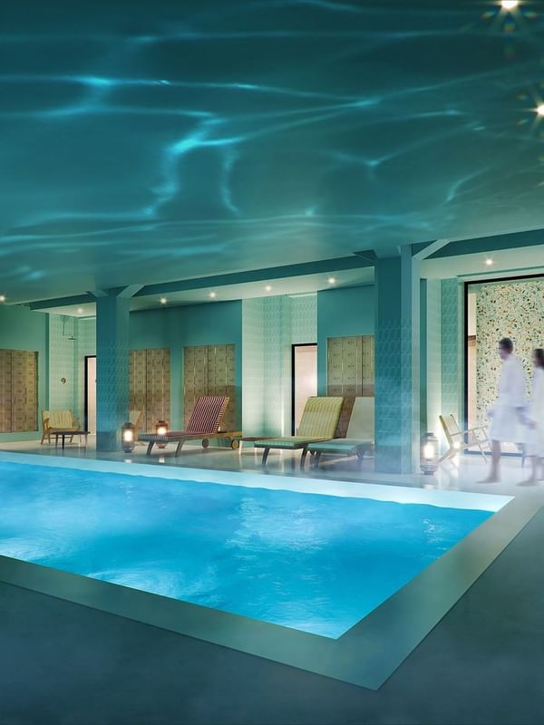 Serene indoor pool with teal walls and soft lighting; a woman swims as two guests in robes at Oceania Hotels