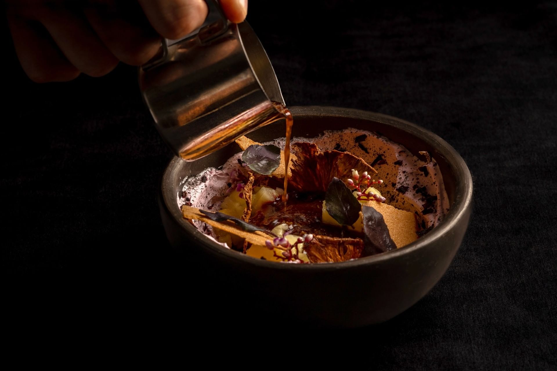 Elegant dessert showing a rich chocolate sauce being poured into a creative bowl served at Cala Luna Boutique Hotel