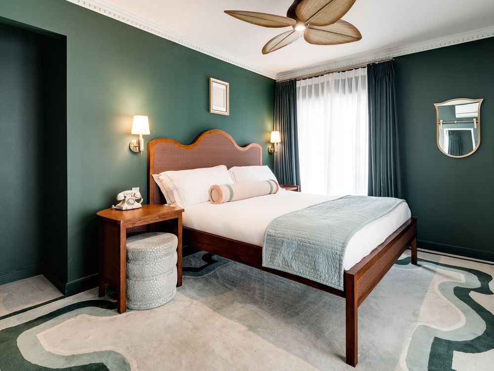 A wide view of a hotel room with a king-sized bed, desk, and window