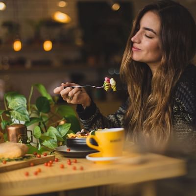 A girl enjoying her meal in a restaurant at The Originals Hotels