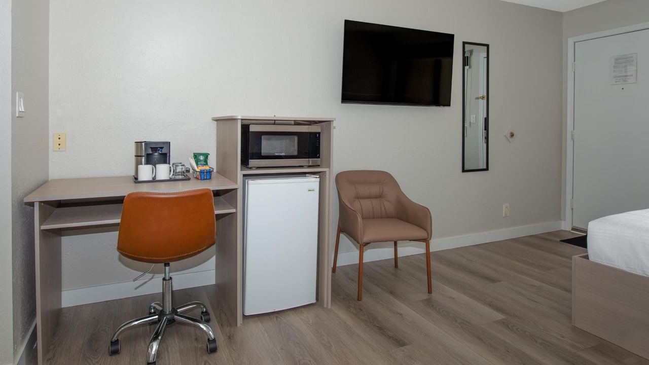 Guest room at Coast Red Deer Hotel with desk, microwave, mini fridge and seating area
