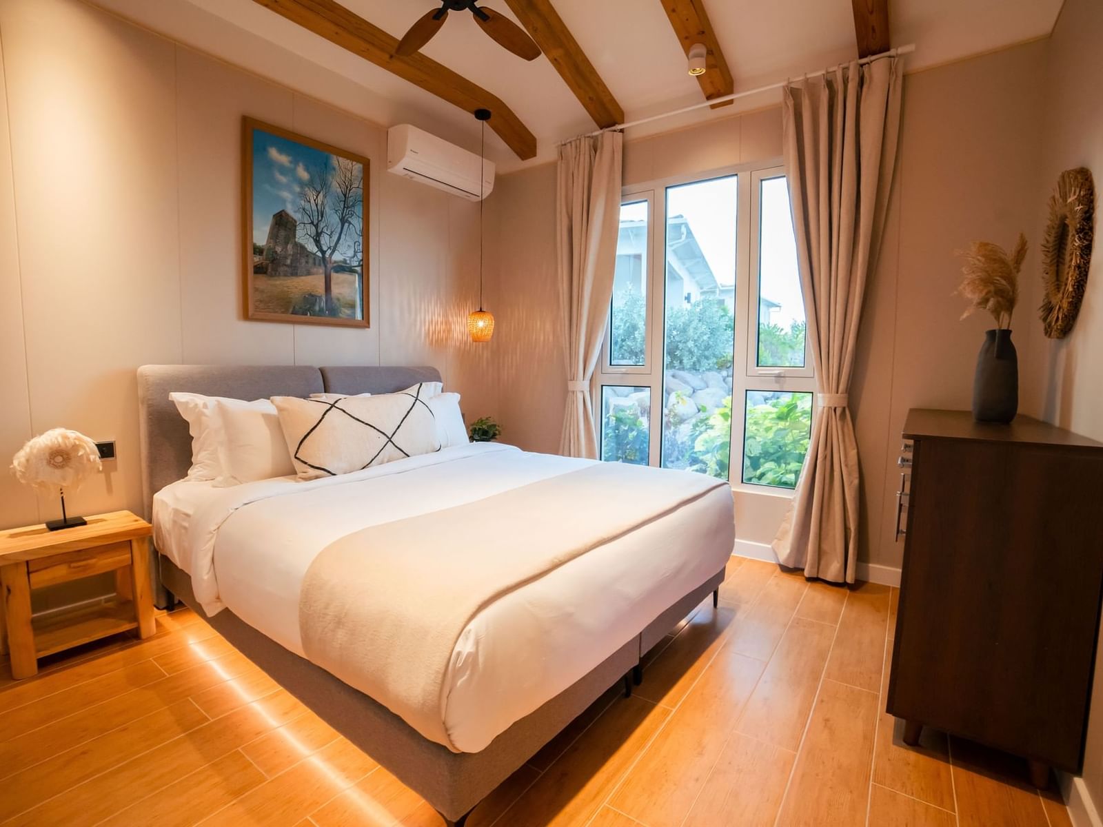 Nachtkastje en zijkast bij het bed in Two-Bedroom Cottage met houten vloer bij Golden Rock Resort