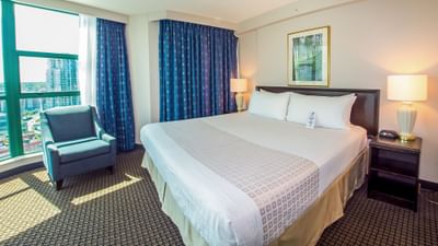Cozy lounger by the bed in Deluxe King Suite at Rosedale on Robson, one of the best hotel suites in Vancouver, BC, Canada