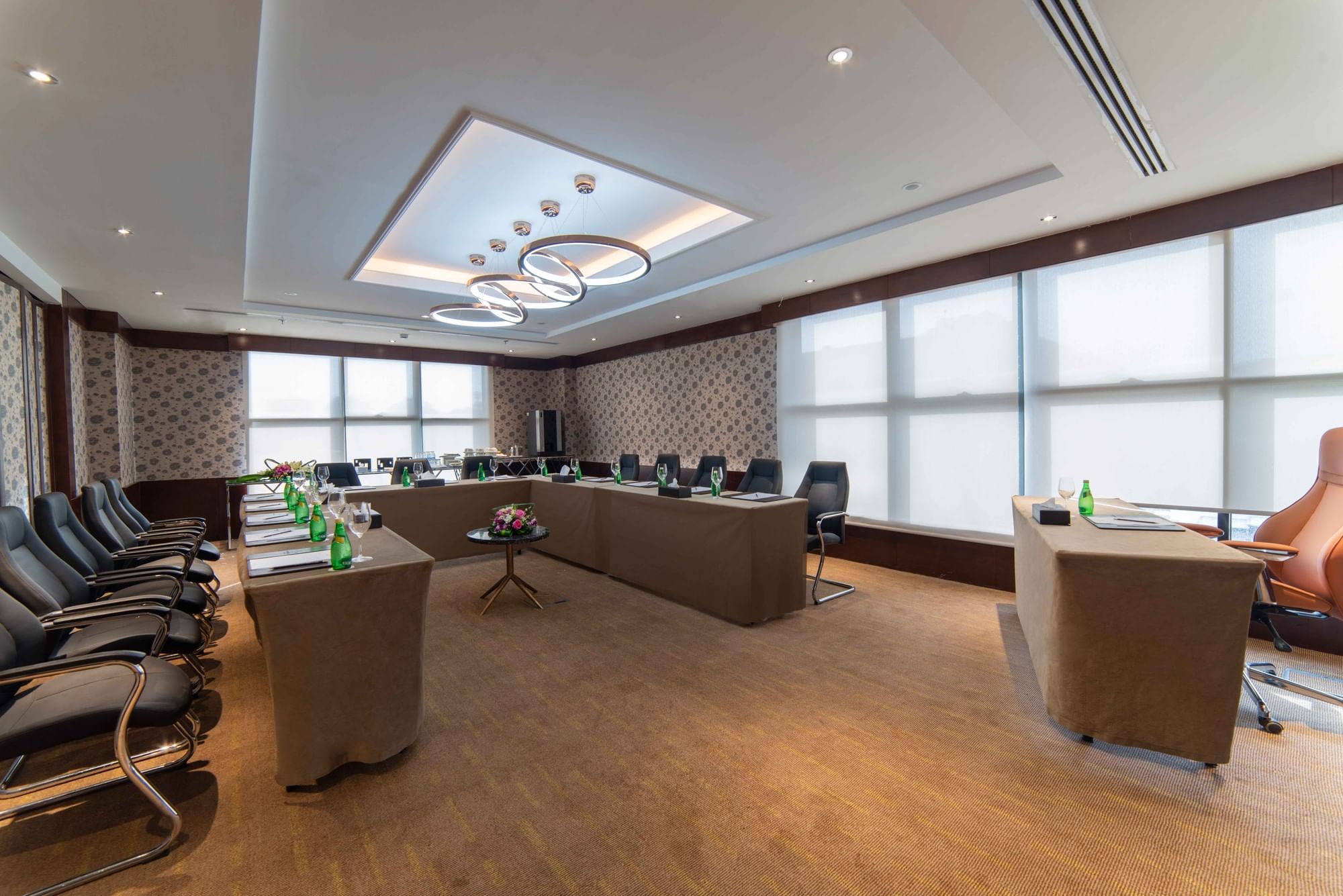 Professional meeting layout with ergonomic black chairs and tan linens under minimalist ring lighting at Warwick Al Khobar