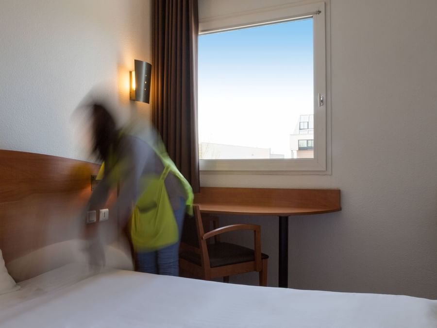 A lady arranging a bed in a room at Hotel Agora