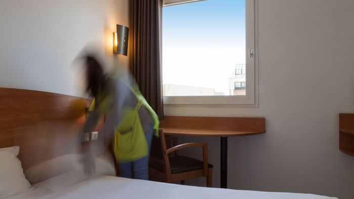 A lady arranging a bed in a room at Hotel Agora