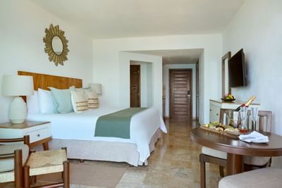 A sophisticated and bright hotel room featuring a luxury king-size bed and modern minimalist layout.