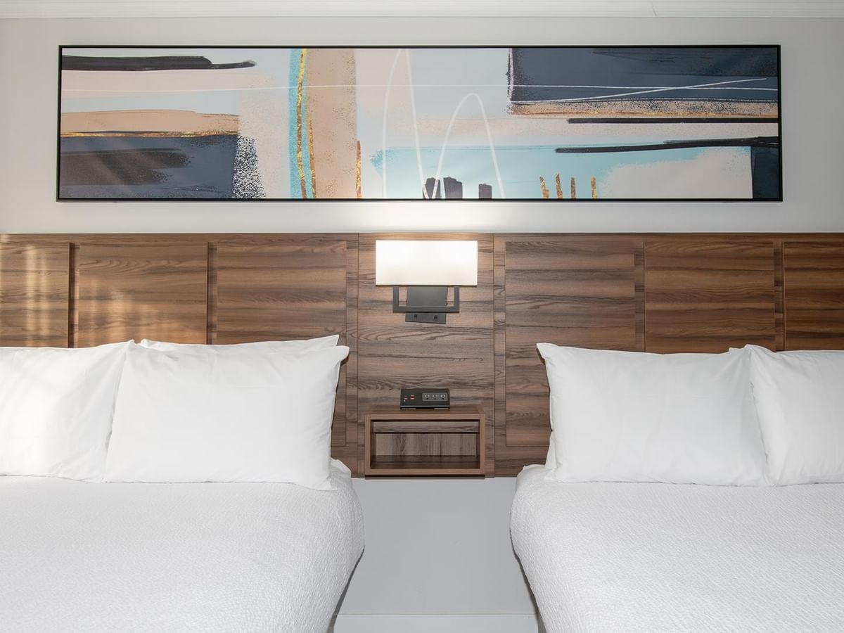 Two beds with white bedding and a modern abstract painting.