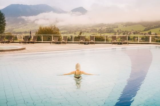 Gast im beheitzten Outdoor Pool im IMLAUER Hotel Schloss Pichlarn