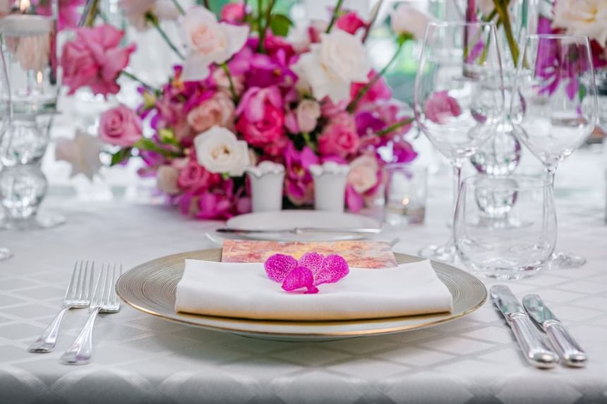 Elegant dining table set with pink floral centerpieces, gold and white place settings at Park Hyatt Saigon