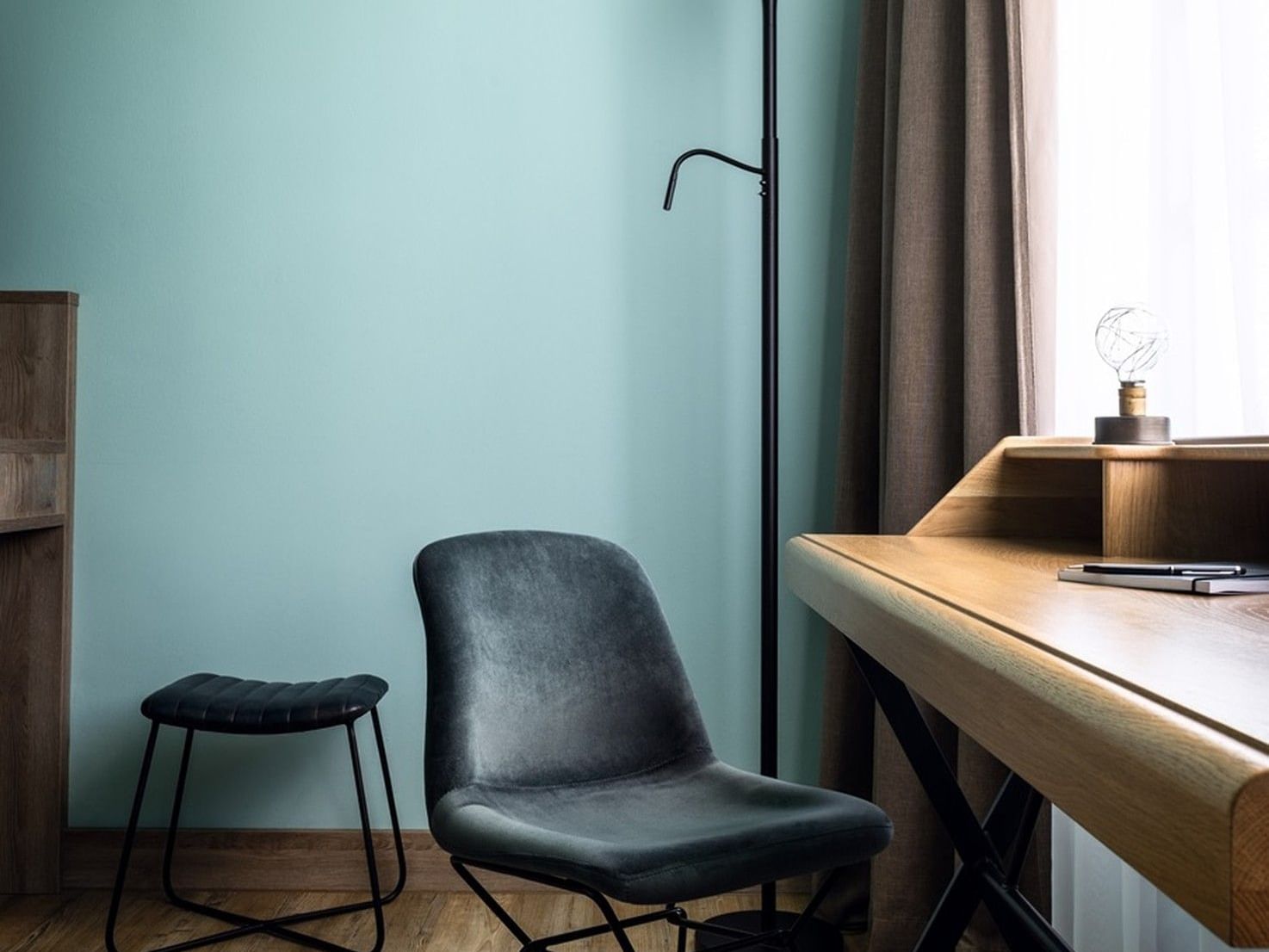 Cozy room with wooden desk, black chair, and floor lamp at Abion Spreebogen Waterside Hotel Berlin.