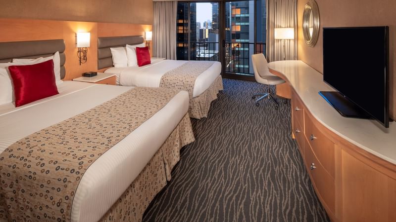 TV facing two beds and city view in Premier Double Queen Room at Warwick Hotels & Resorts