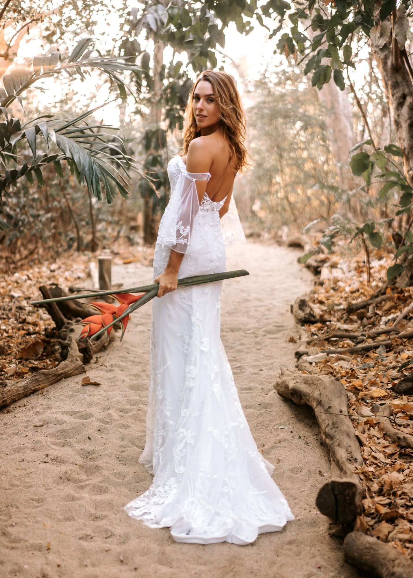 Bride in a white lace dress walking through the lush, tropical garden paths at Cala Luna Boutique Hotel