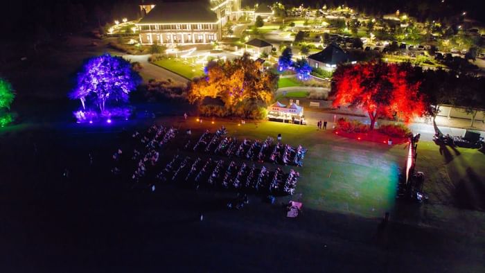 Aerial view of a night-time event at Camp Creek Inn with colorful trees and rows of chairs in a grassy field.