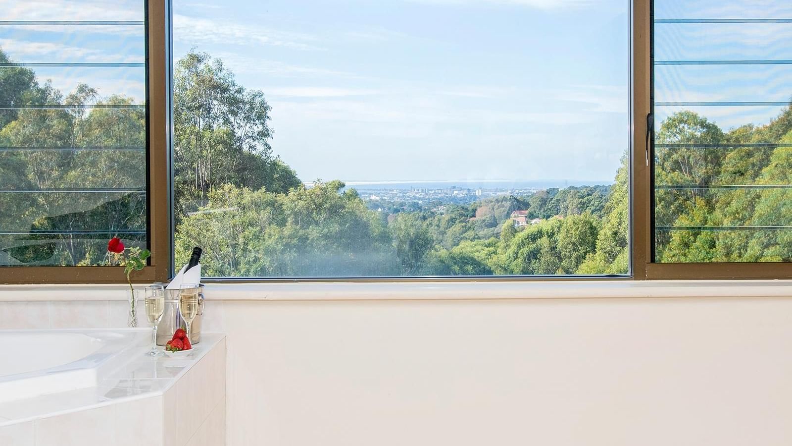 Champagne, rose & strawberries by the bathtub with a distant city view in Privilege King Spa room at Mercure Charlestown