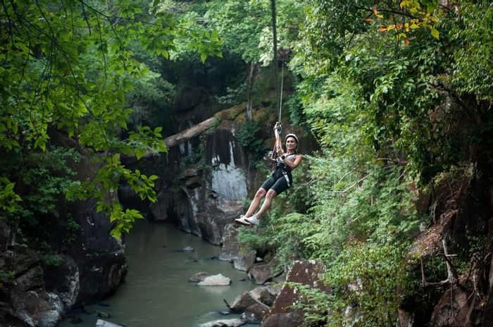 Lady zip lining over the river alongside the forest near Hotel Rio Perdido