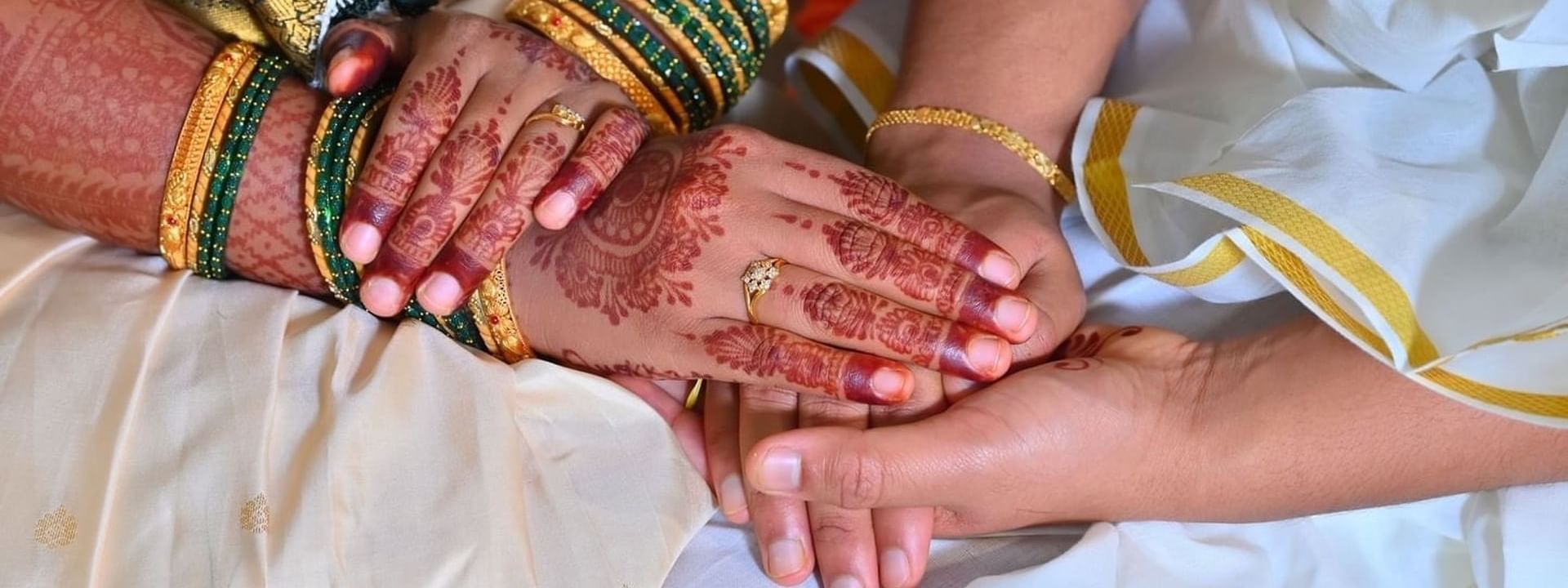 Close-up of two hands with intricate henna designs, adorned with bangles and a ring at APA Hotel Woodbridge